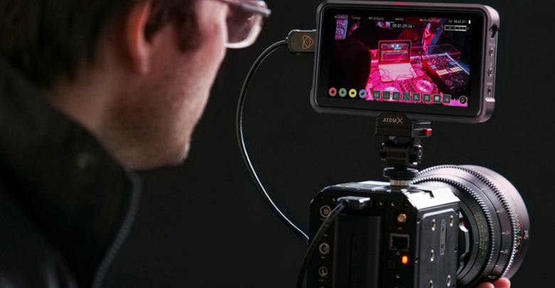 Man looks at the Ninja V field monitor atop a camera.
