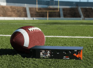 A rugby ball and a black encoder on a field
