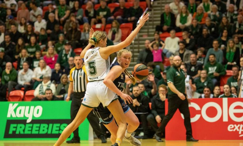 Two women jostling for the basketball during a live basketball match.